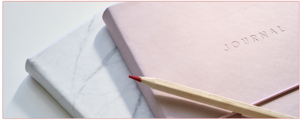 Inspirational Prompts for Christmas, woman drinking hot chocolate and writing in her journal with a candy cane as decoration