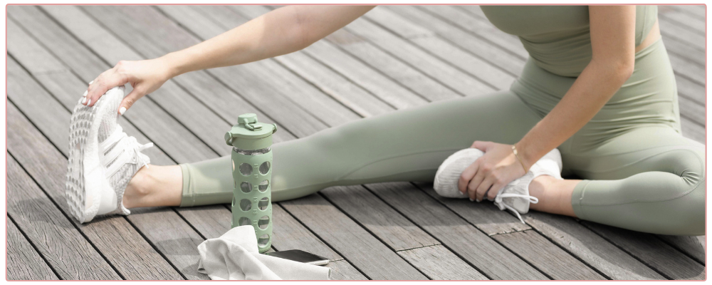 Woman stretching, wearing sage coloured yoga gears with sage water bottle for blog post 4 niching myths debunked